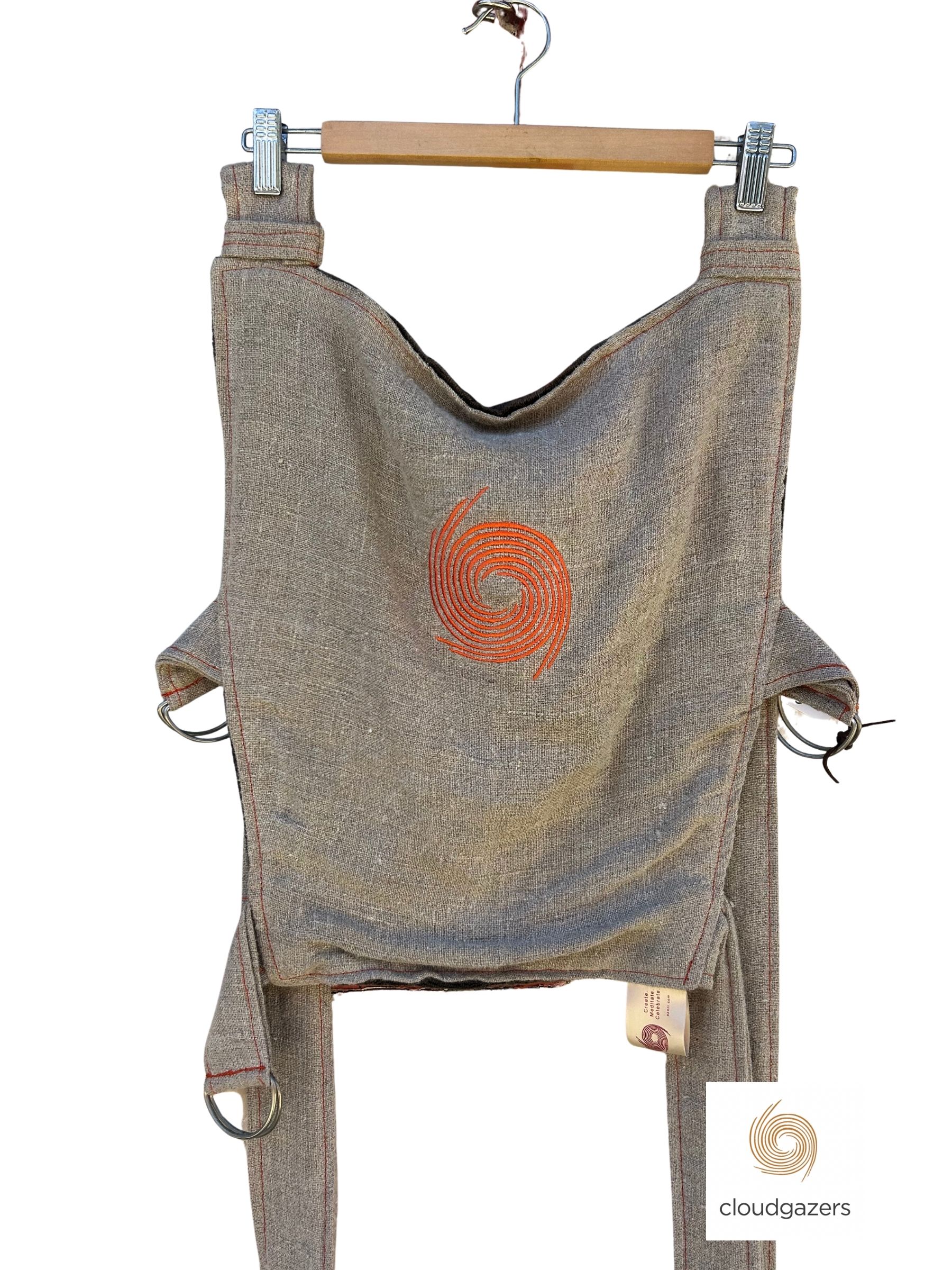 Handmade Baby Carrier One-of-One with signature orange swirl detail, crafted from sustainable materials with adjustable straps.