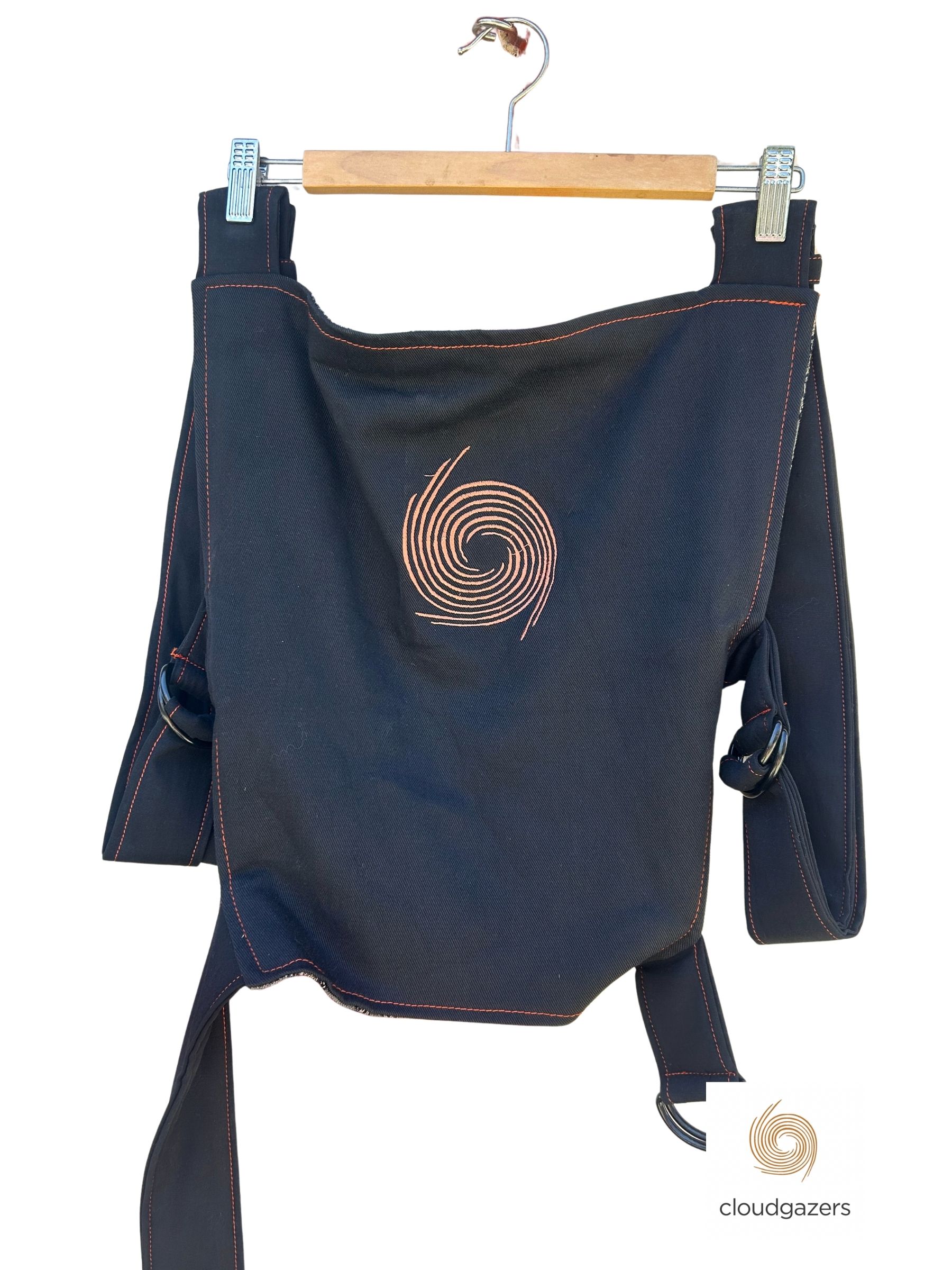 Handmade Baby Carrier One-of-One in dark fabric with orange swirl design, showcasing sustainable fashion and craftsmanship.